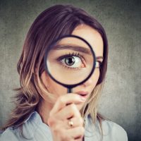 Curious woman looking through a magnifying glass